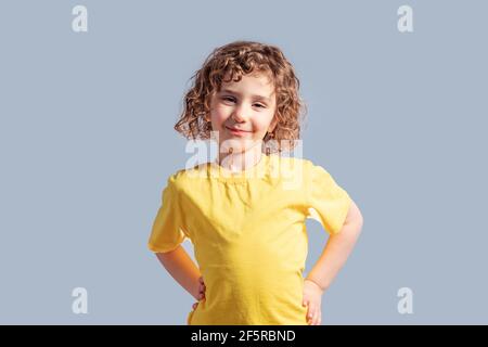 Adorabile bambino di 5 anni in T-shirt gialla in posa su grigio Foto Stock