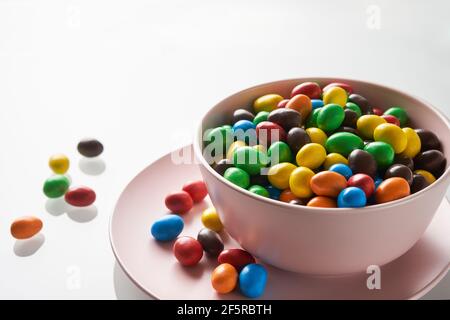 Una caramella luminosa cade in una ciotola rosa. Atmosfera festosa. Foto Stock