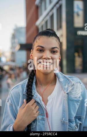 Donna hipster felice con elegante acconciatura ascolto di musica all'aperto Foto Stock