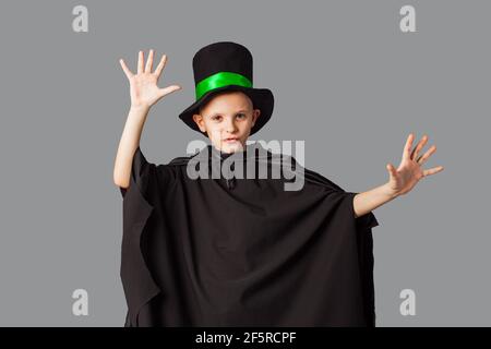 Giovane mago che esegue un trucco. Ragazzino con cappello e mantello mago nero. Foto Stock