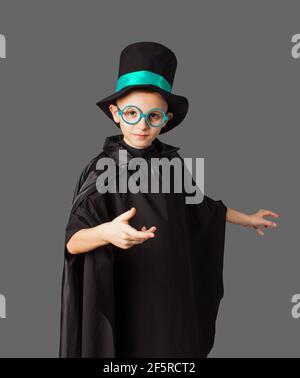 Giovane mago che esegue un trucco. Ragazzino con cappello e mantello mago nero. Foto Stock