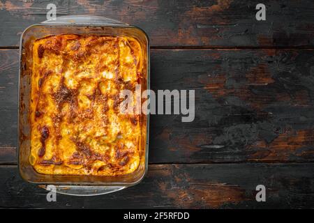 Cucina Italiana. Set Lasagna caldo e gustoso appena sfornato, in teglia da forno, su sfondo vecchio tavolo di legno scuro, vista dall'alto, piatto, con spazio per la copia del testo Foto Stock