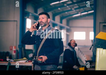 Uomo che parla per telefono con il controllo di un ponte gru Foto Stock