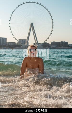 donna che nuota in mare giocando con onde che sorridono larghe Foto Stock