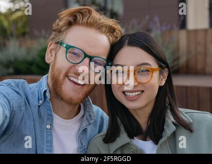 Primo piano ritratto di una coppia sorridente che indossa occhiali eleganti prendendo selfie Foto Stock