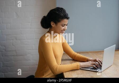 Bella donna copywriter lavoro freelance progetto, digitando, cercando informazioni. Ritratto di un giovane programmatore afroamericano di successo Foto Stock