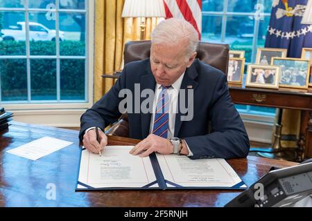 Il presidente degli Stati Uniti Joe Biden firma il Save Lives Act in legge durante una cerimonia nell'Ufficio ovale della Casa Bianca 25 marzo 2021 a Washington, D.C. la legge consente all'Amministrazione dei Veterani di fornire vaccinazioni COVID-19 a tutti i veterani, i loro coniugi e gli operatori sanitari. Foto Stock