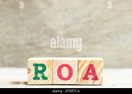 Lettera alfabetica nella parola ROA (Abbreviazione del rendimento delle attività) su sfondo di legno Foto Stock