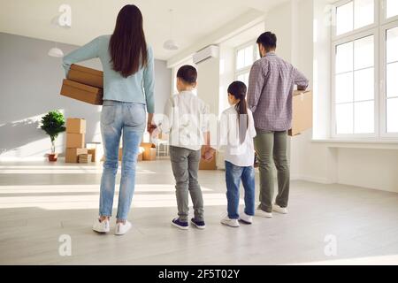 Vista posteriore su genitori e bambini in fila insieme con scatole in una nuova casa Foto Stock