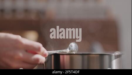 mano dell'uomo mescolare la pasta di fettuccine in pentola con il closeup di acqua bollente , foto ampia Foto Stock