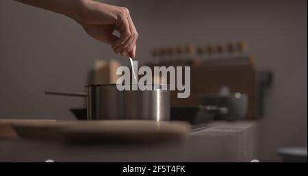 mano dell'uomo mescolare la pasta di fettuccine in pentola con il closeup di acqua bollente , foto ampia Foto Stock