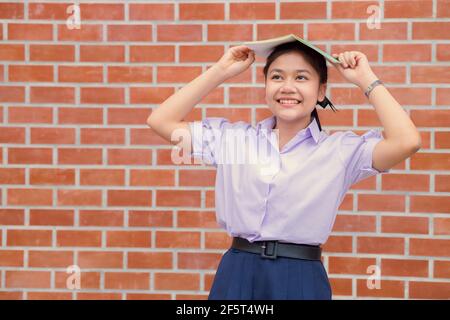 Asian ragazza teen studente uniforme sorriso felice con libro per l'istruzione di ritorno a scuola concetto. Foto Stock