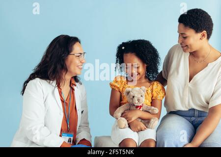 Bambina che ha esame medico da medico femminile mentre è con la madre nella clinica. Pediatra che esamina una paziente di ragazza. Foto Stock