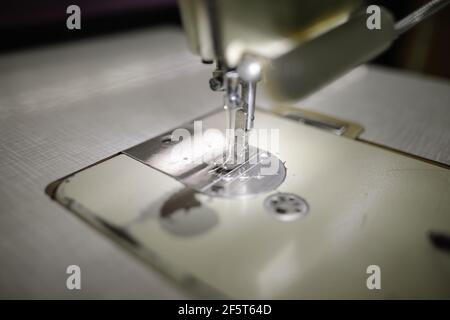 Immagine della profondità di campo poco profonda (fuoco selettivo) con una macchina elettrica per cucire in una fabbrica tessile. Foto Stock