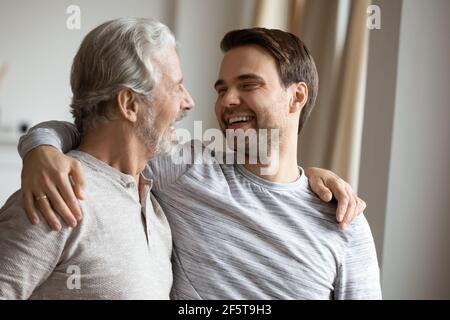 Sorridente padre maturo e figlio adulto che abbracciano Foto Stock