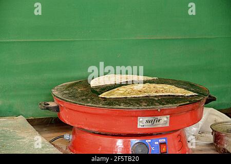 Preparazione del qutab, un piatto azerbaigiano a base di pasta sottilmente arrotolata ripiena di verdure che viene cucinata brevemente su una griglia Foto Stock