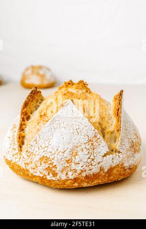 Delizioso pane rotondo con farina sulla superficie dorata panetteria su sfondo bianco Foto Stock