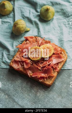 Delizioso toast di prosciutto iberico, formaggio e fichi freschi sulla tovaglia blu, delizioso antipasto, ideale come aperitivo. Cibo sano Foto Stock