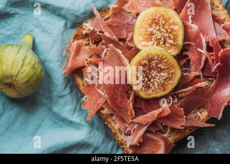 Delizioso toast di prosciutto iberico, formaggio e fichi freschi sulla tovaglia blu, delizioso antipasto, ideale come aperitivo. Cibo sano Foto Stock