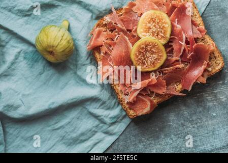 Delizioso toast di prosciutto iberico, formaggio e fichi freschi sulla tovaglia blu, delizioso antipasto, ideale come aperitivo. Cibo sano Foto Stock