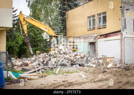 Demolizione di un vecchio edificio. Smantellamento e schiantamento di casa da parte di macchinari per la nuova costruzione. Industria Foto Stock