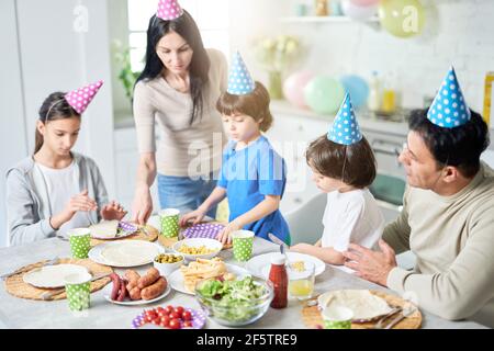 Preparazione. Madre latina di mezza età che si prende cura della sua famiglia mentre cenano, festeggiando il compleanno insieme a casa Foto Stock