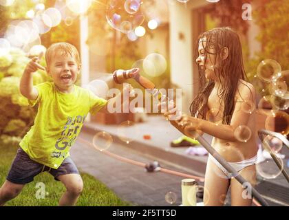 I bambini si divertono con la doccia estiva in giardino Foto Stock