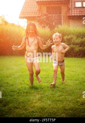 I bambini si divertono con la doccia estiva in giardino Foto Stock