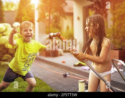 I bambini si divertono con la doccia estiva in giardino Foto Stock