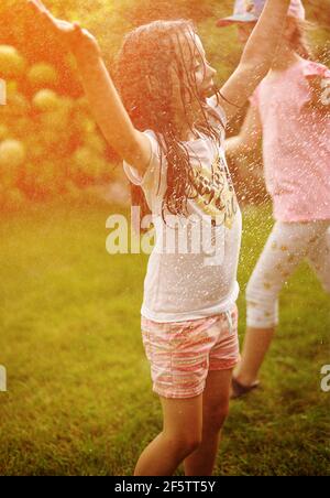 I bambini si divertono con la doccia estiva in giardino Foto Stock