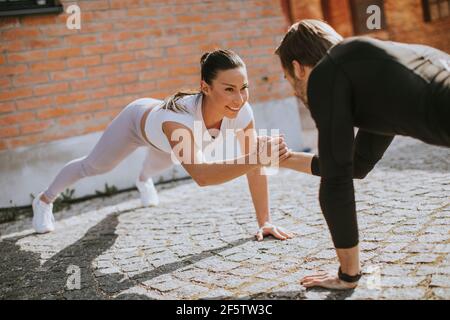 Bella giovane coppia doung un braccio pushup esercizio in ambiente urbano Foto Stock