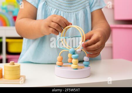 Primo piano delle mani di una bambina caucasica di due anni, giocando con i giocattoli didattici montessori. Foto Stock
