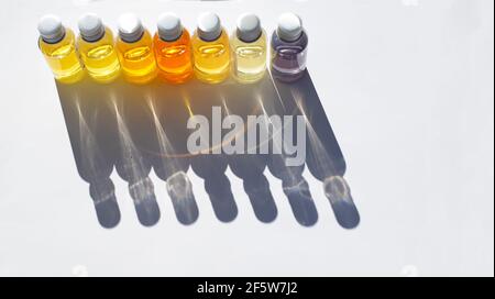 I flaconcini con olio di fragranza sono in fila. Le ombre ricci cadono su uno sfondo bianco. Foto Stock