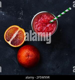 Succo d'arancia rosso in un bicchiere. Cocktail dalle arance siciliane. Idea estiva creativa minima Foto Stock