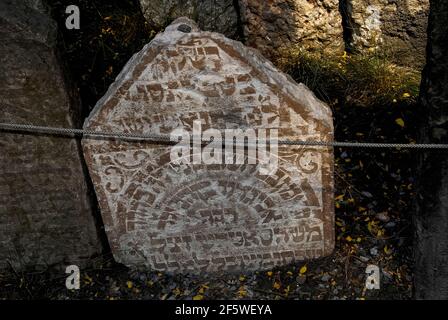 Pietre o ciottoli lasciati in cima a questa antica lapide, secondo la tradizione e l'abitudine ebraica, indica che qualcuno ha visitato la tomba nel vecchio cimitero ebraico di Josefov, il quartiere ebraico di Praga, capitale della Repubblica Ceca. La lapide, con un'iscrizione ebraica scolpita in rilievo, è tra circa 12,000 crammed in quasi 350 anni nello spazio murato del centro della città, con circa 100,000 abitanti dell'ex ghetto che giacciono in un massimo di 12 strati al di sotto di essi. La prima lapide risale al 1439 e l'ultima interazione risale al 1787. Foto Stock