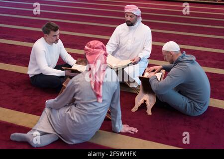 Gruppo di musulmani che leggono, recitano e ricordano Quran durante il ramadanInside moderna e nuova moschea Foto Stock