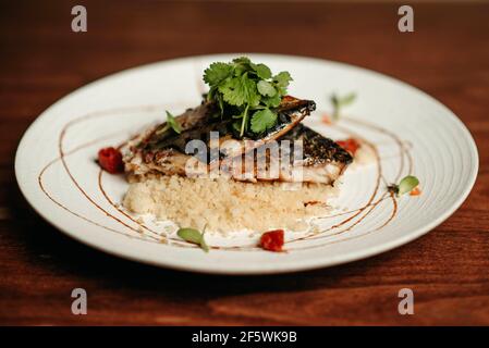 Sgombro grigliato e couscous su un piatto bianco Foto Stock