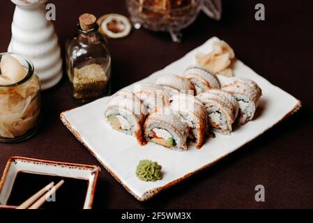 Sushi con anguilla, cosparso di salsa, su un tavolo splendidamente decorato Foto Stock