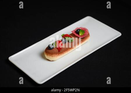 Delizioso tiramisù dessert con fragole e more su sfondo nero Foto Stock