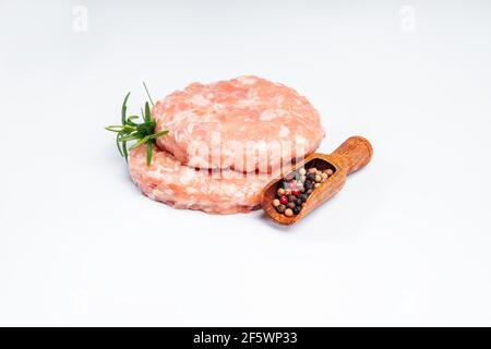 Hamburger di pollo su un piatto bianco con pepe nero e un rametto di rosmarino. Fast food per casa e ristoranti. Semilavorato, carne di pollo veloce Foto Stock