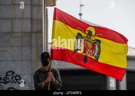 Madrid, Spagna. 28 Marzo 2021. Un sostenitore del dittatore Franco che detiene una bandiera spagnola precostituzionale durante un incontro di sostenitori di estrema destra ad Arco de la Victoria, commemorando l'82° anniversario in cui il dittatore Francisco Franco e le sue forze sono entrati a Madrid in seguito al colpo di Stato spagnolo del luglio 1936 contro la 2° Repubblica spagnola. Credit: Marcos del Mazo/Alamy Live News Foto Stock