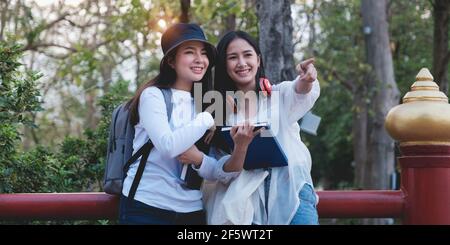 Due giovani studenti universitari che si divertono a fare escursioni nel parco e indicano qualcosa quando sono interessanti. Studio, istruzione, università, università Foto Stock