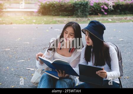 Due studenti si trovano all'università durante la lettura di un libro e della comunicazione. Studio, istruzione, università, università, concetto di laurea. Foto Stock