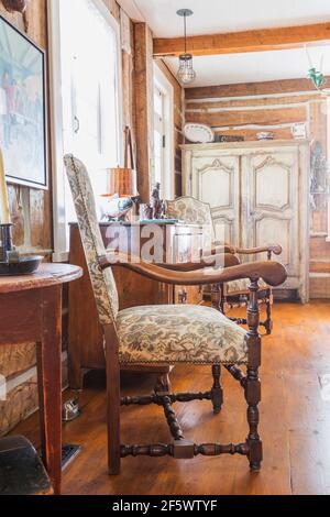 Poltrone in legno Luigi XIII rivestite in beige, marrone e motivi floreali di borgogna, latticello afflitto, armoire marrone in soggiorno all'interno della vecchia casa Foto Stock