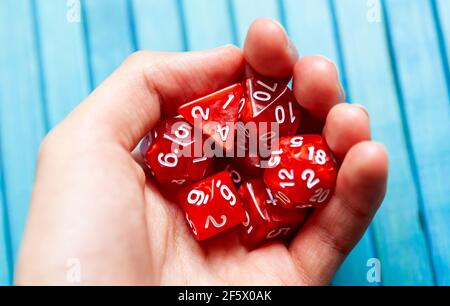 Mano piena di dadi da tavolo rosso poliedrico RPG gioco da tavolo, closeup. Uomo che tiene un mucchio di dadi di gioco alla moda, un sacco di dadi utilizzati per il gioco di ruolo fantasia impostazione Foto Stock