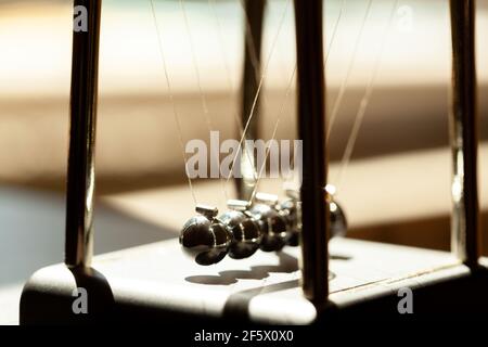 Culla Newtons classica alla luce del sole, dof poco profondo, palle di metallo ancora macro, closeup estremo. Slancio, fisica dei movimenti e leggi fisiche comuni, semplici Foto Stock