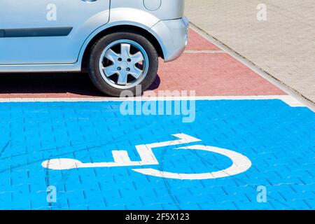 Parcheggio blu per disabili, disabili. Simbolo della sedia a rotelle dipinto a terra, spazio per il parcheggio, guardaroba, vista angolare, nessuno. Foto Stock