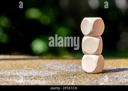 Tre cubetti vuoti di legno impilati, spazio per la copia, spazio per simboli, all'aperto, all'esterno struttura a torre costruita, mockup dei cubetti, closeup, sfondo verde sfocato Foto Stock