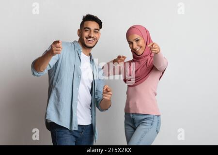 Vi scegliamo. Allegra coppia musulmana che punta le dita verso Camera Foto Stock