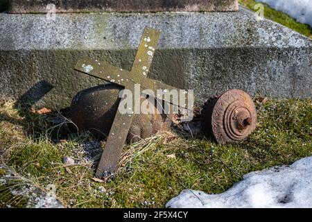 Croce arrugginita caduta accanto al monumento funebre nel cimitero ortodosso orientale di Hietaniemi o cimitero di Helsinki, Finlandia Foto Stock